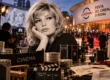 Monica Vitti in primo piano, con il tappeto rosso della Festa del Cinema di Roma e le attrezzature dell’industria cinematografica sullo sfondo.